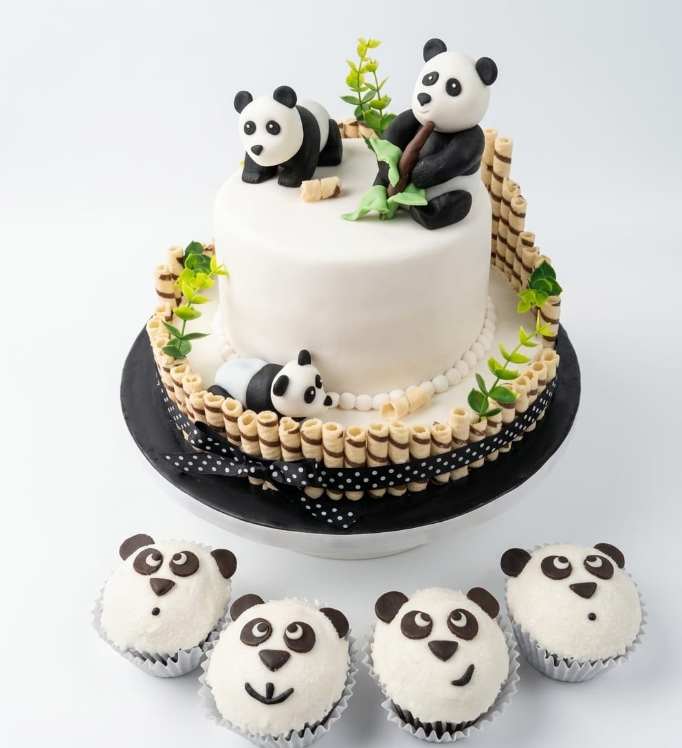 Torta de baby shower con osos panda modelados a mano y cupcakes con caritas de panda